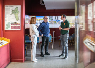 Mary Keaveney (WDC), Ian Brannigan (WDC), and Daniel Curly (Rathcroghan Visitor Centre) talking beside an exhibition in the Rathcroghan Visitor Centre.